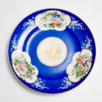Large, circular Popov porcelain dish with gilt Russian eagle and three panels of flowers on a blue ground